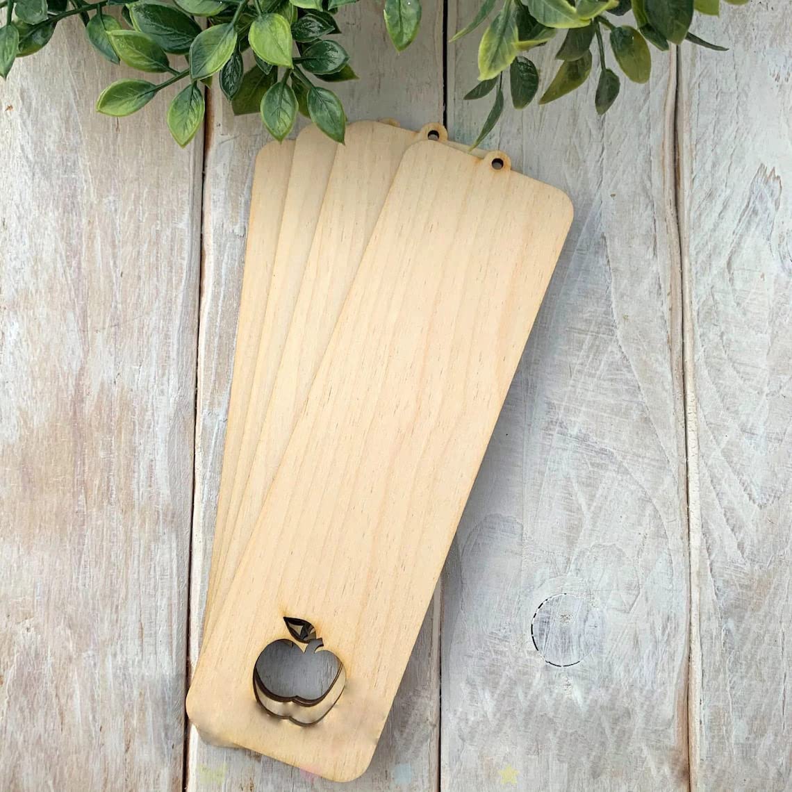 Three wooden cutting boards with apple carvings on a rustic wooden surface.