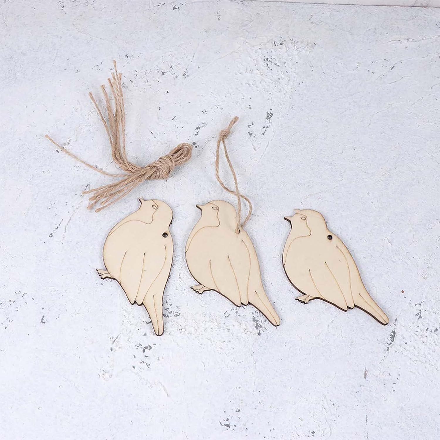 Three wooden bird ornaments hanging on a textured white surface