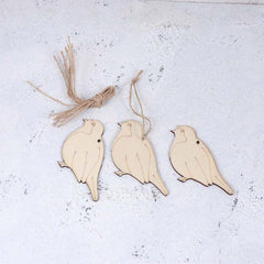 Three wooden bird ornaments hanging on a textured white surface