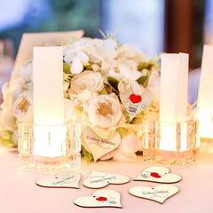 Decorative setup with candles, flowers, and heart-shaped cards on a table.