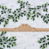 Decorative wooden arch with green leafy branches on a marble background