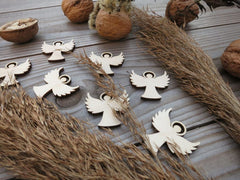 Wooden angel figurines on a wooden surface with wheat and nuts.
