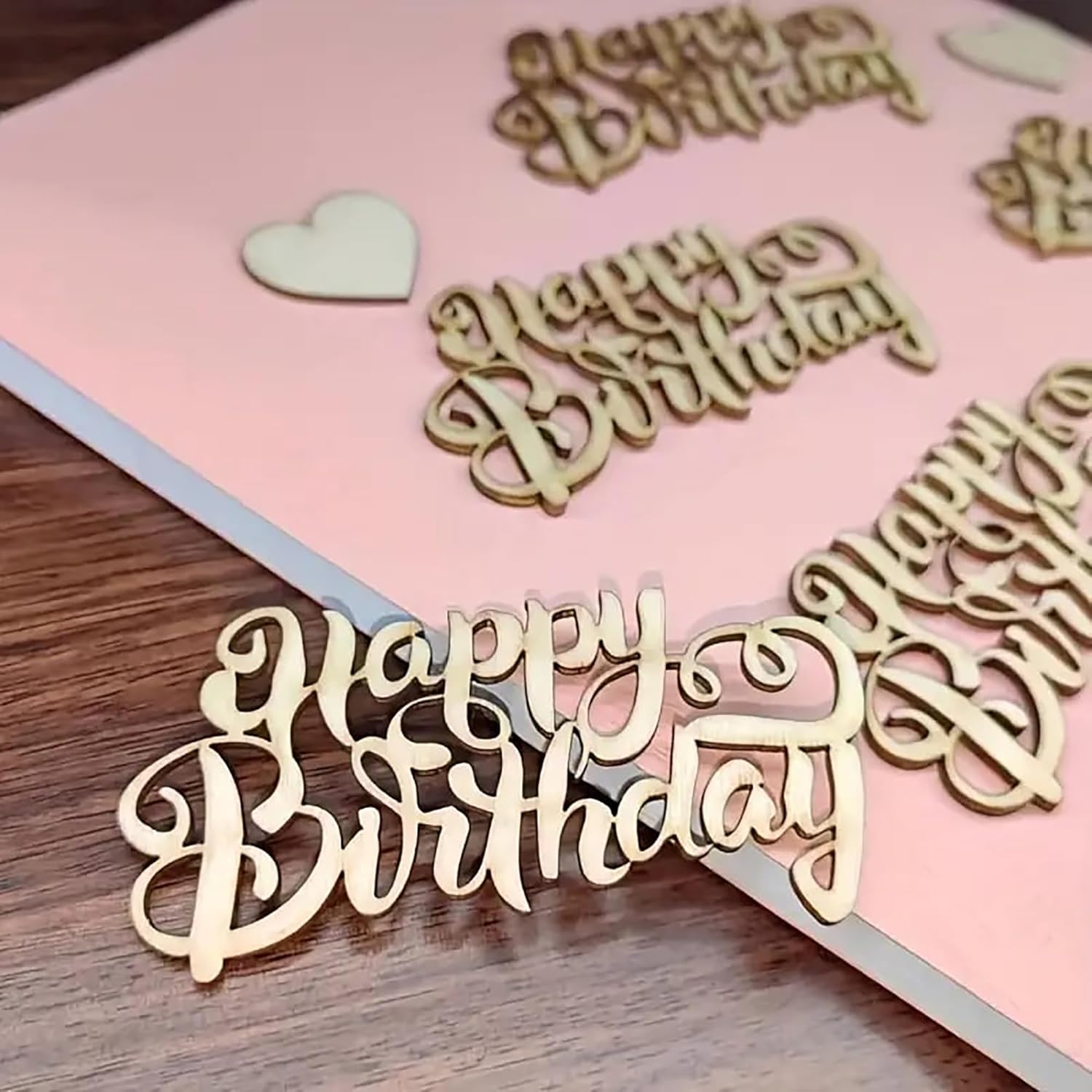 Wooden 'Happy Birthday' decorations on a pink card with a heart.