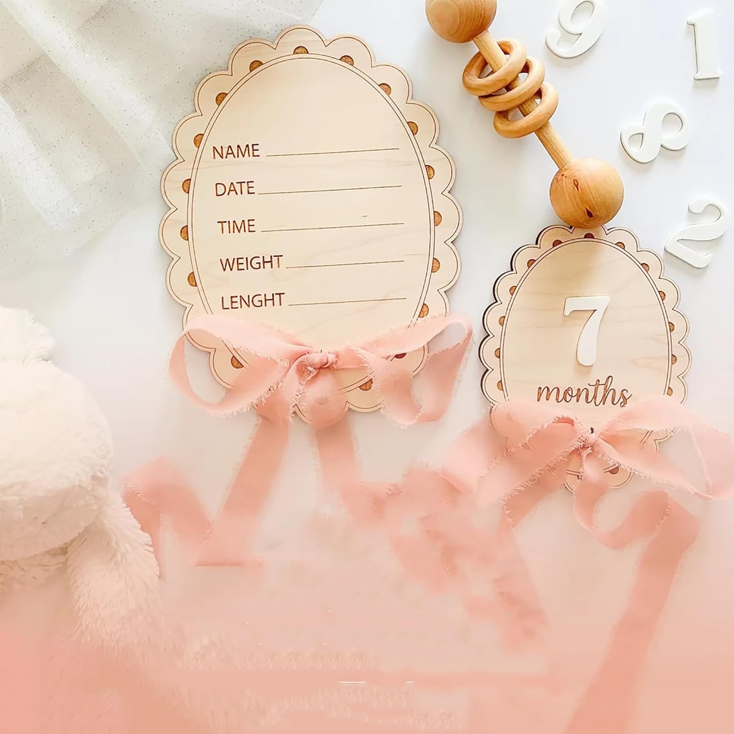 Baby milestone cards with wooden ribbons and decorative elements on a soft pink background