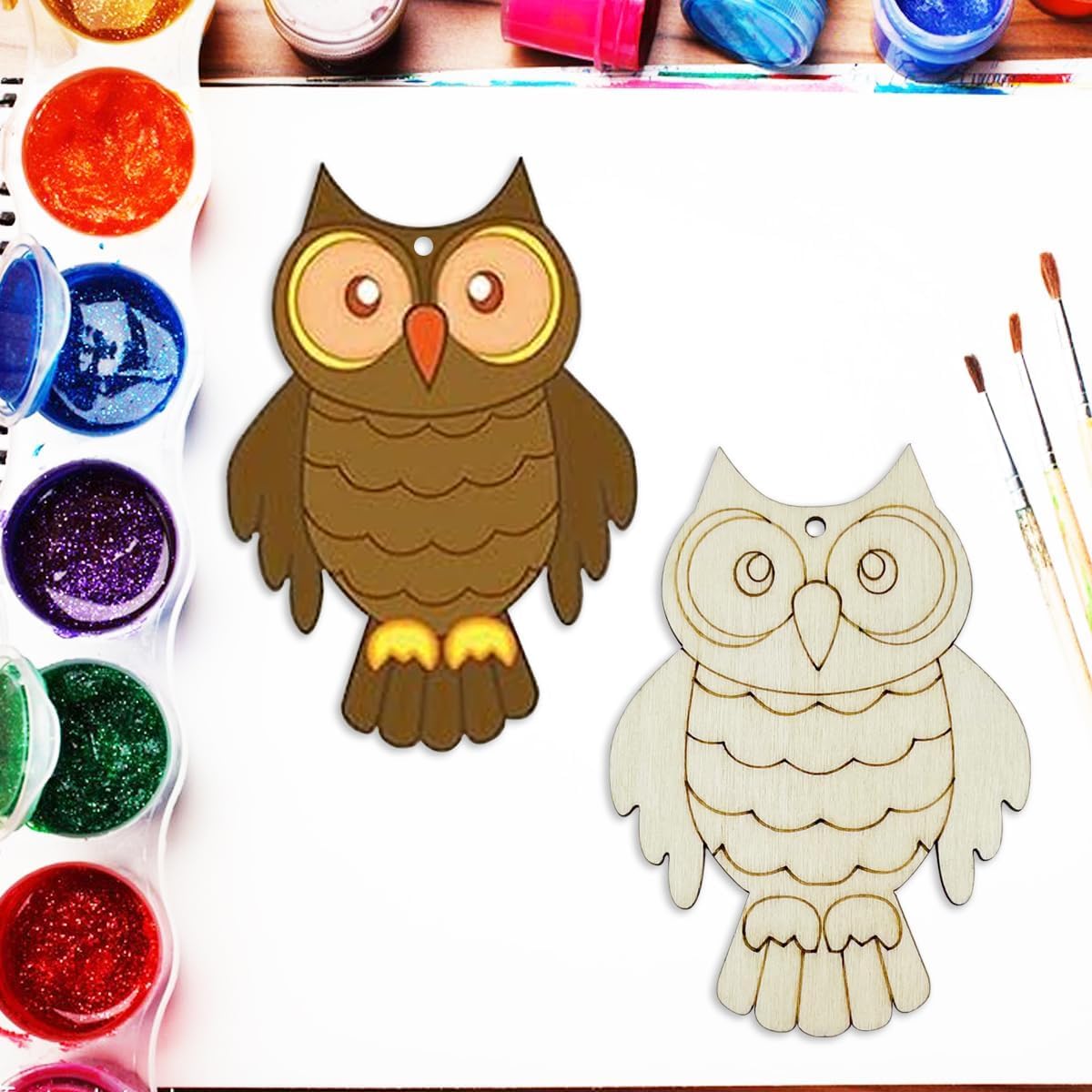 Two owl-shaped wooden cutouts with paint supplies on a white background