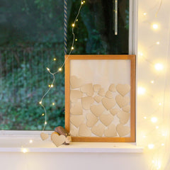 Framed artwork with heart patterns on a surface with string lights