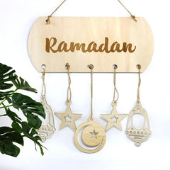 Wooden 'Ramadan' sign with hanging decorations on a white background