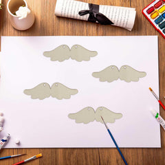Paper cutouts of angel wings on a table with art supplies