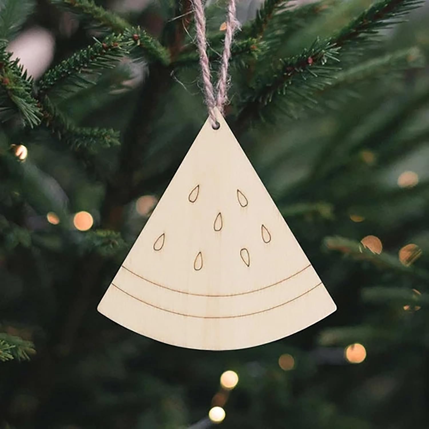 Wooden Christmas ornament shaped like a triangle with cut-out patterns, hanging on a tree.