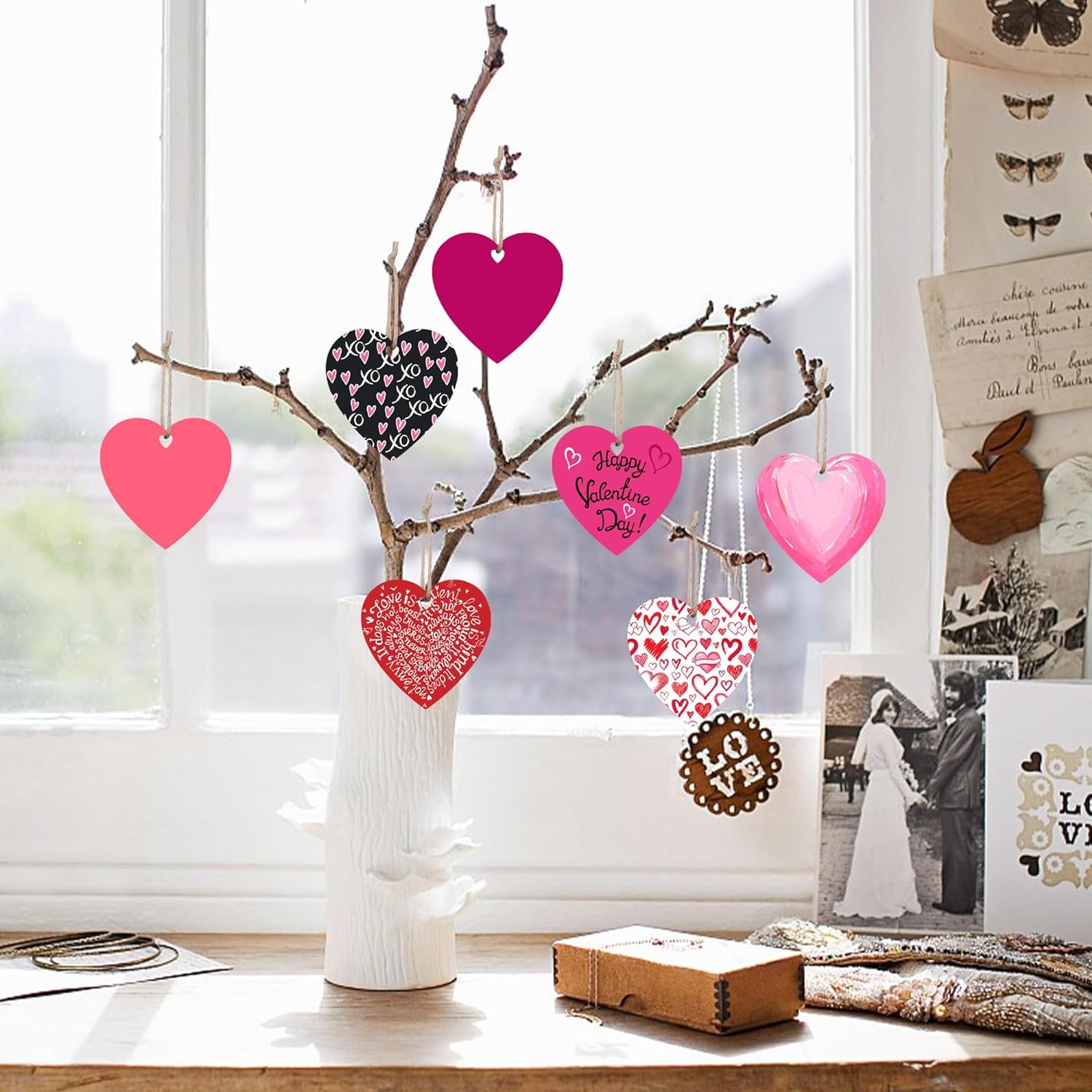 Decorative branch with heart-shaped ornaments in a vase on a table.
