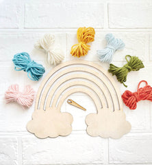 Wooden rainbow with yarn balls on a white tiled background
