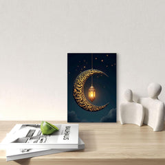 Decorative wall art with a crescent moon and Arabic calligraphy on a dark blue background, placed on a wooden surface with a magazine and decorative items.