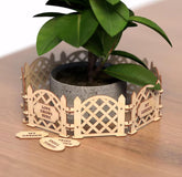 Wooden garden fence planter with a potted plant on a wooden surface