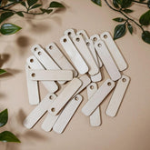 Set of wooden tags on a beige surface with green leaves around