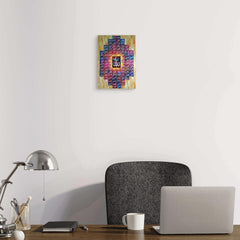 Colorful abstract painting on a white wall above a desk with a laptop and lamp.