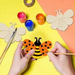 Children's hands painting a paper bee craft on a colorful background