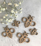 Wooden bee-shaped objects on a textured surface with white flowers.