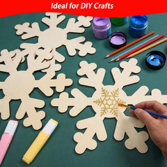 Wooden snowflakes with paint supplies on a green surface, ideal for DIY crafts.