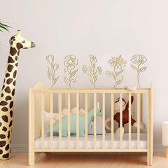 Wooden crib with stuffed animals and a tall plush giraffe in a room with floral wall art.