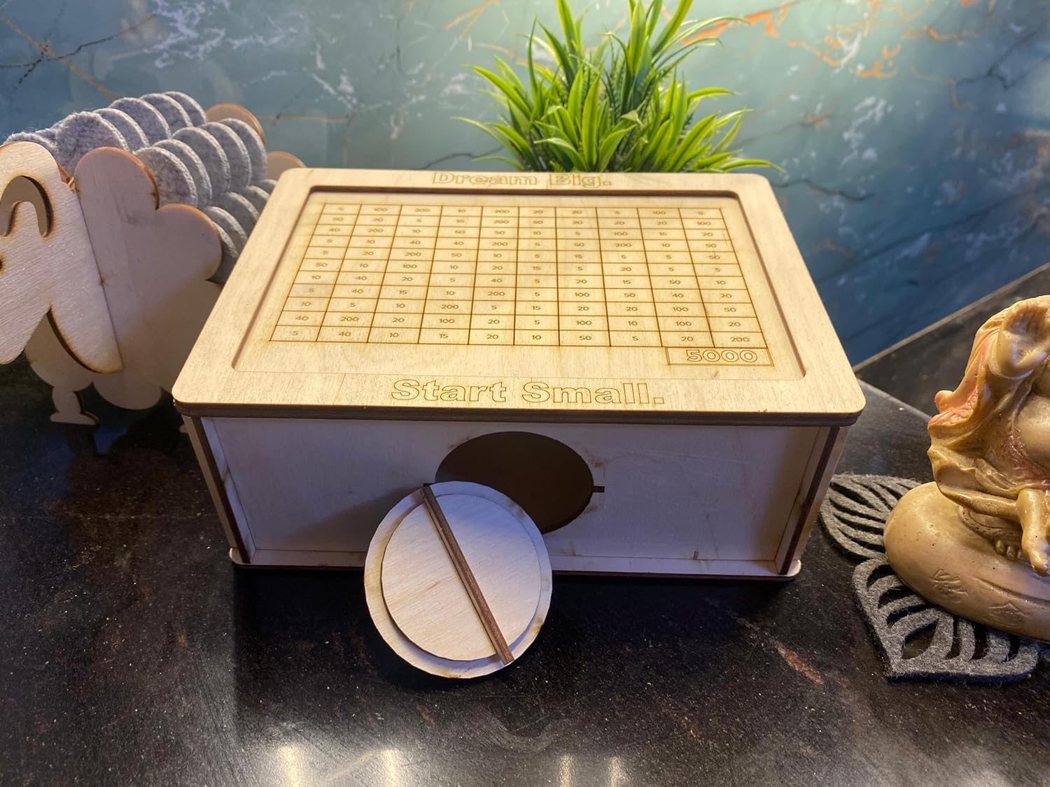 Wooden toy with grid pattern and 'Start Small' text on a dark surface with decorative elements.