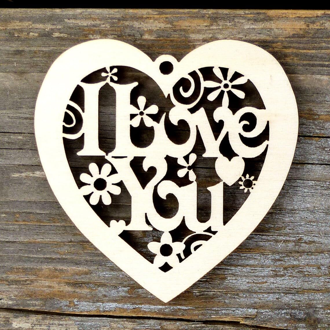 Heart-shaped wooden cutout with 'I Love You' text on a wooden background