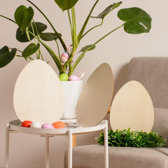 Decorative egg-shaped lamps on a table with a plant and colorful eggs in the background.