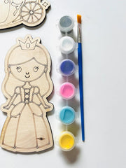 Wooden princess cutout with paint supplies on a white background