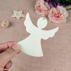 White angel cutout held by a hand on a textured surface with flowers in the background
