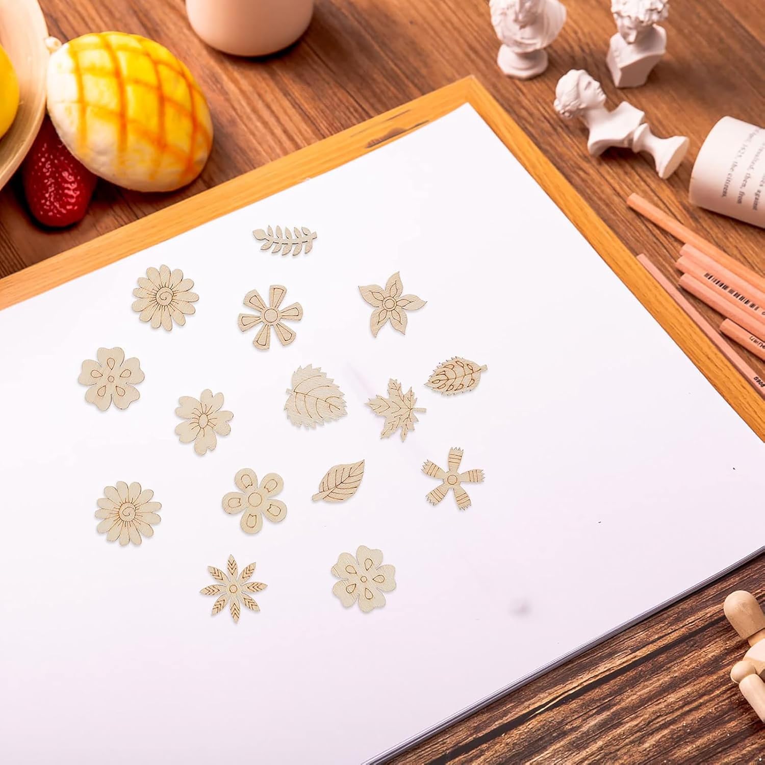 Decorative flower and leaf stickers on a white sheet of paper with a wooden desk background.