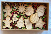 Box of wooden Christmas ornaments including gingerbread men, snowflakes, and Santa Claus.