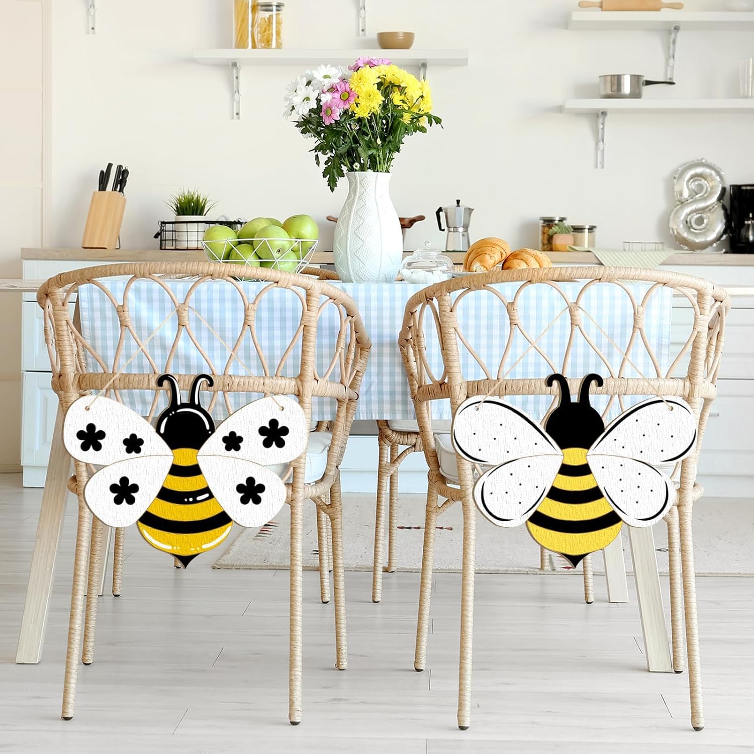 Two decorative bee-shaped chairs with a table and kitchen items in the background.