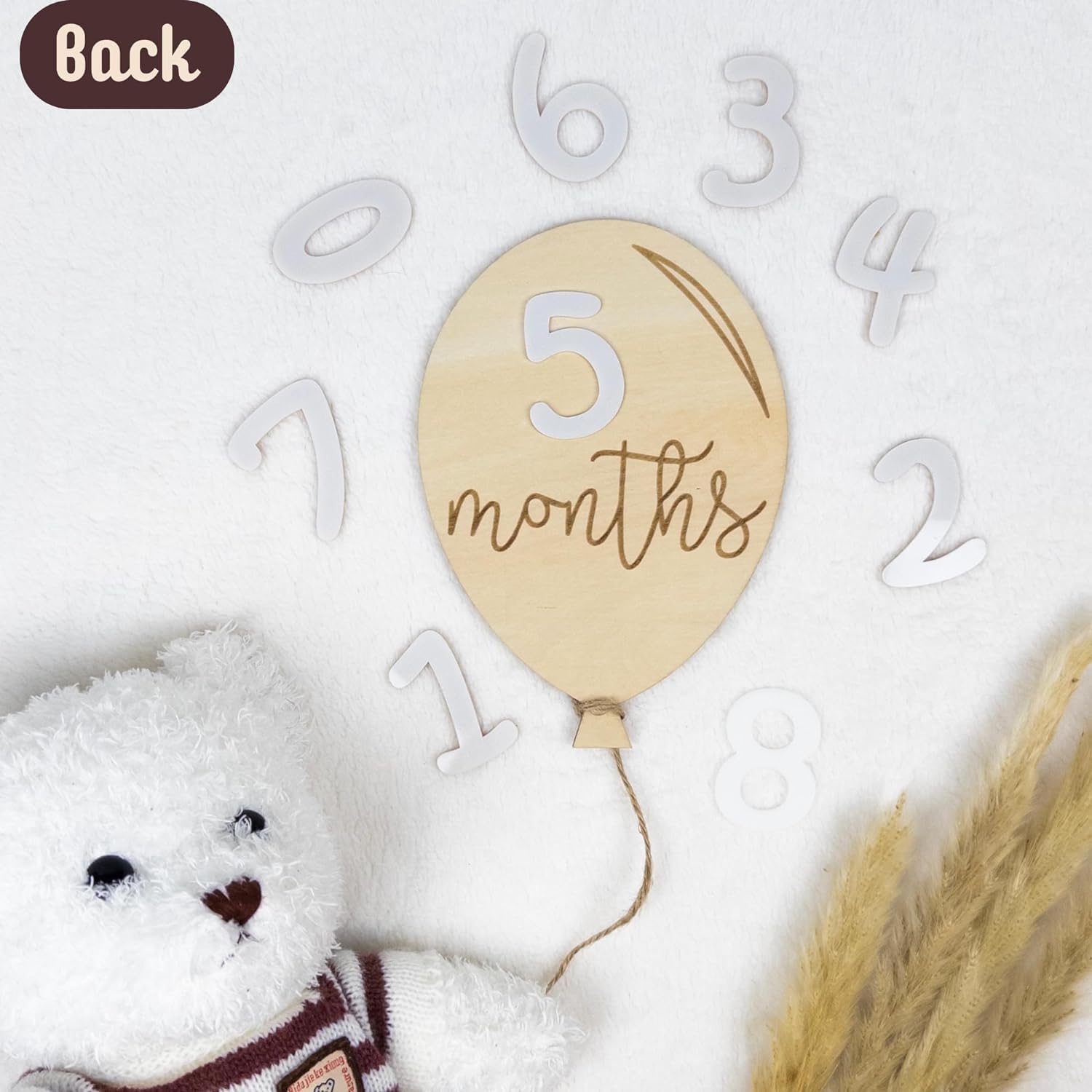 Wooden balloon with '5 months' text on a white background with decorative elements.