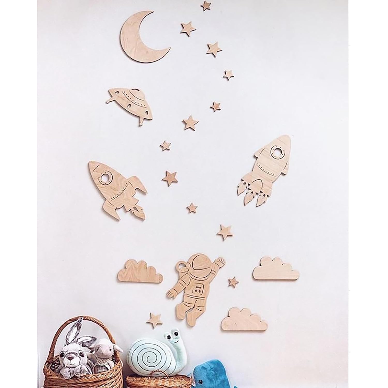 Wooden space-themed wall decorations including rockets, stars, and an astronaut on a light pink background.