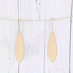 Two gold teardrop-shaped pendants hanging on a string against a light wooden background.