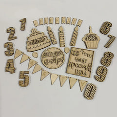 Collection of wooden birthday-themed decorations on a white background
