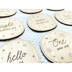 Wooden milestone discs with text for baby's age on a blue blanket