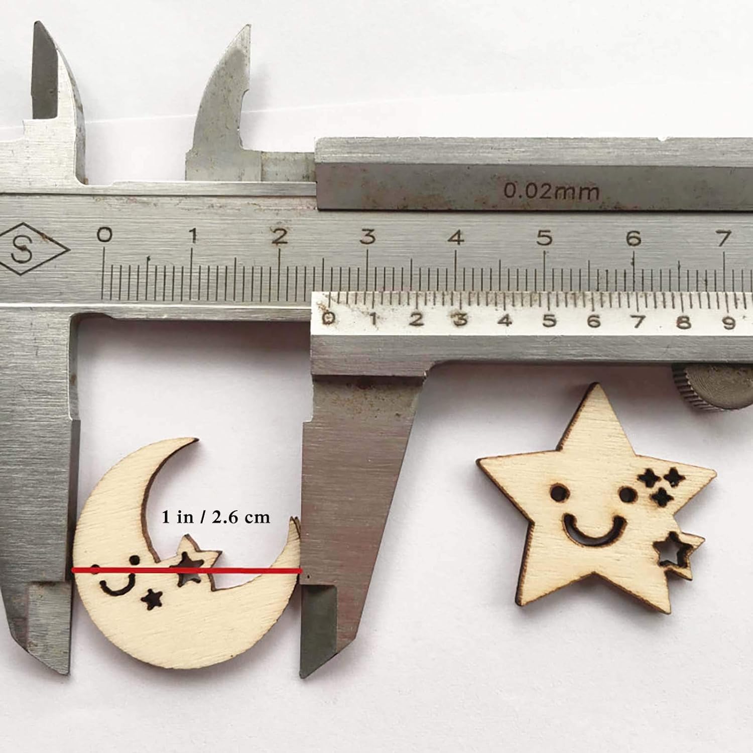 Wooden moon and star shapes with smiley faces on a white background, measured by a caliper.