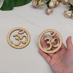 Two wooden coasters with Om symbol on a light surface with flowers in the background
