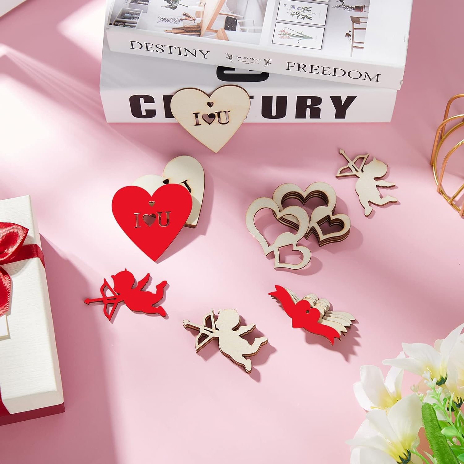 Decorative heart and angel figurines on a pink surface with a book titled 'Destiny Freedom' in the background.