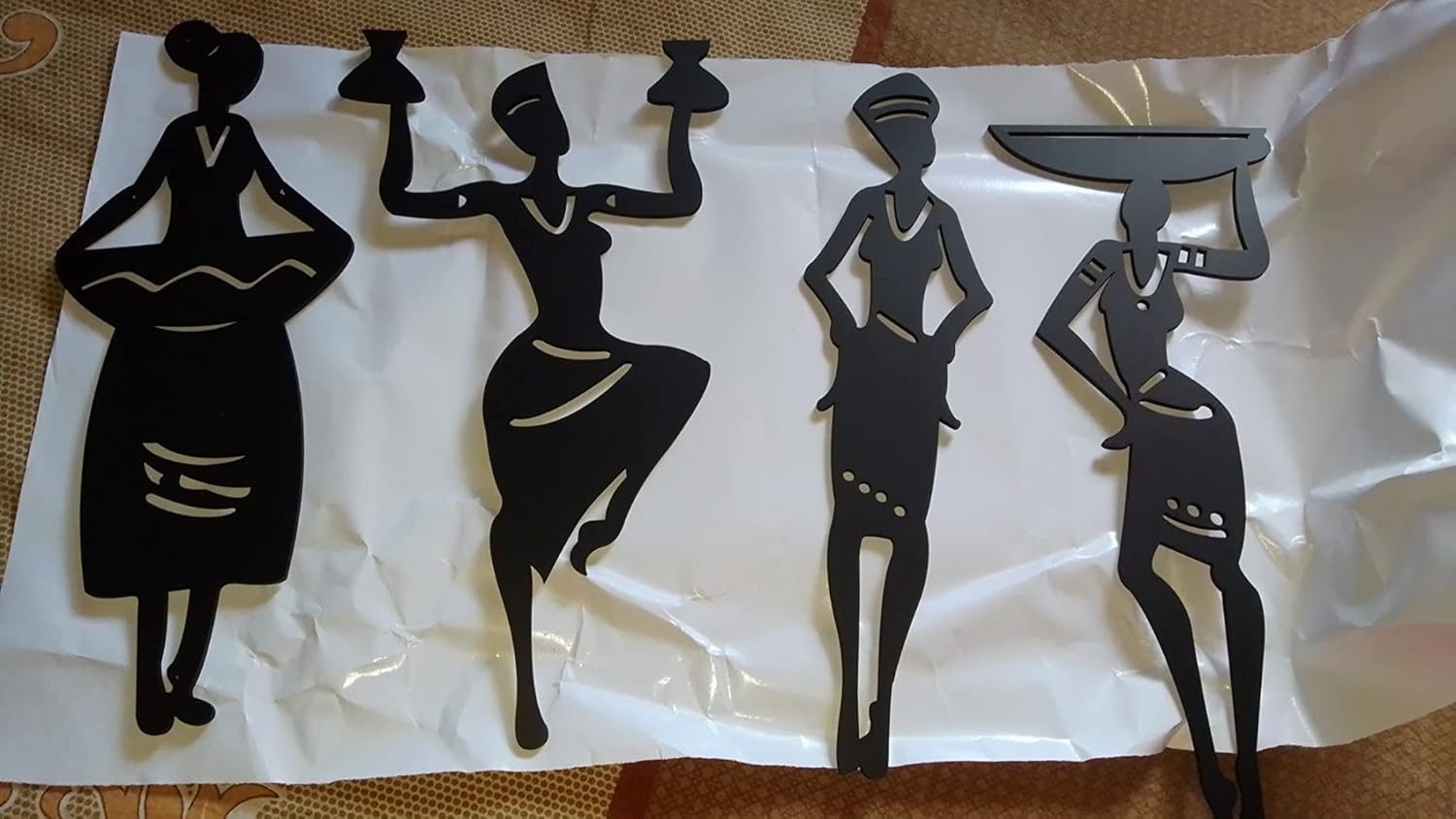 Black silhouette figures of women holding trays on a white sheet