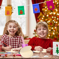 Two children sitting at a table with Christmas decorations and a tree in the background.