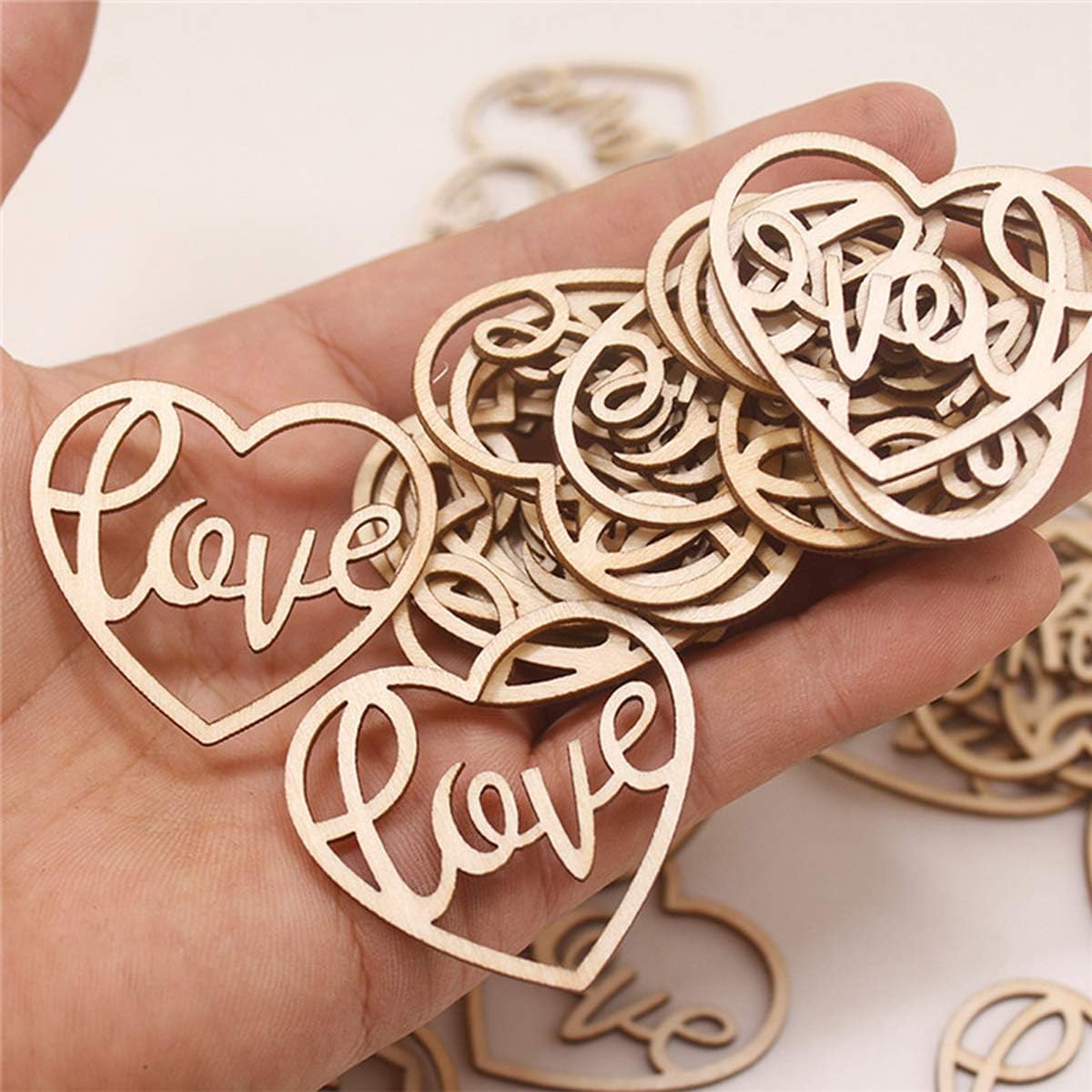 Wooden heart-shaped decorations with 'love' engraving held in a hand.
