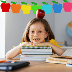 Child with books and an apple on head in a classroom setting