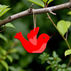 Red bird-shaped ornament hanging from a branch with green leaves in the background