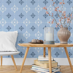 Living room with wooden table, books, and decorative items against a blue patterned wall.