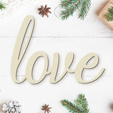 Wooden word 'love' on a white wooden surface with Christmas decorations.