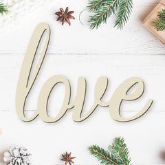 Wooden word 'love' on a white wooden surface with Christmas decorations.