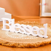 White decorative word 'Blessed' on a textured surface with a warm-toned background