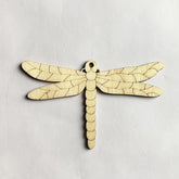 Wooden dragonfly ornament on a light gray background