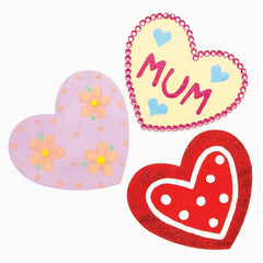 Three heart-shaped decorations with 'MUM' on a yellow heart, flowers on a pink heart, and polka dots on a red heart.